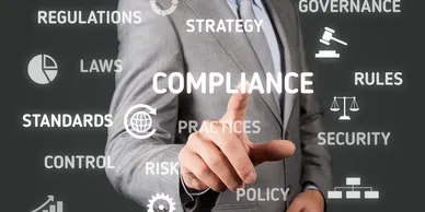 A man pointing to the word compliance on a screen.
