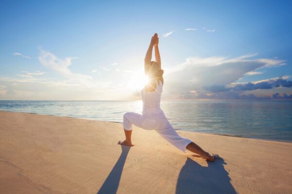 A woman is doing yoga on the beach